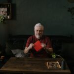 Older man sitting at a table at home surrounded by houseplants